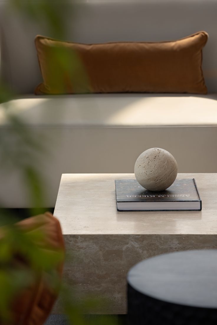 Interior design detail – a travertine coffee table with a stone sphere and art book, styled by a Miami interior photographer