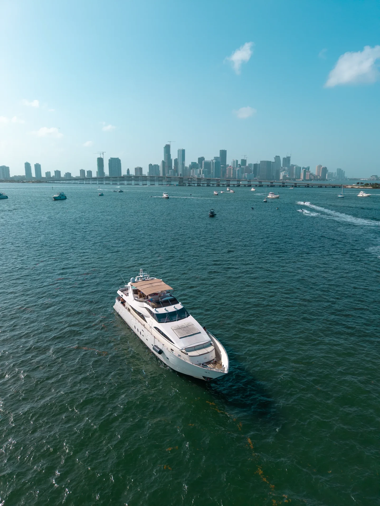 Aerial drone photo of a luxury yacht cruising Biscayne Bay with the downtown Miami and Brickell skyline behind it